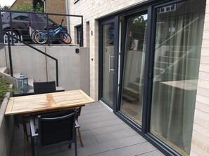 Eine Terrasse mit Tisch und Stühlen, ein Fahrrad und ein geparktes Auto.
