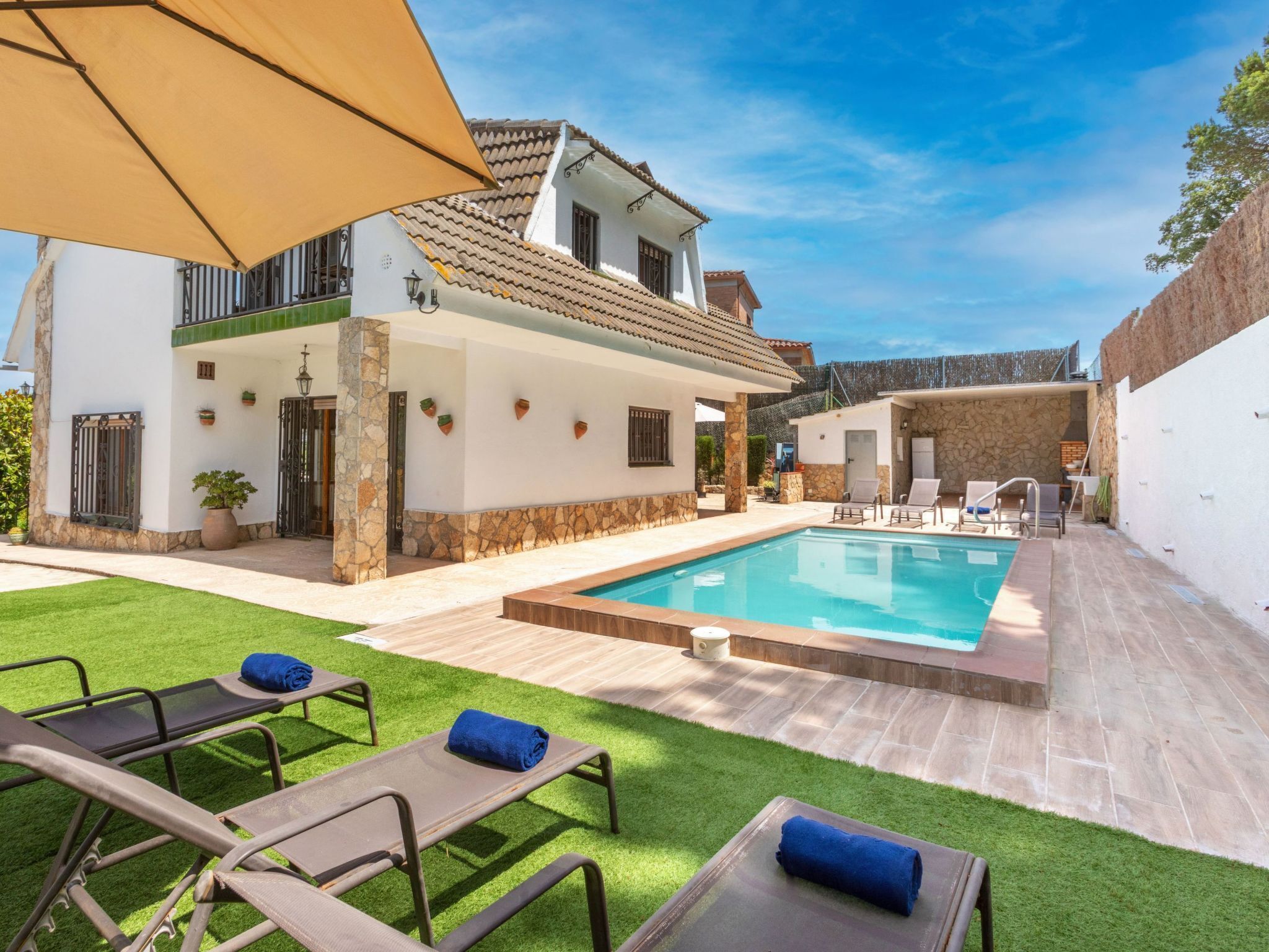 A poolside area with a swimming pool, lounge chairs, and a covered patio.