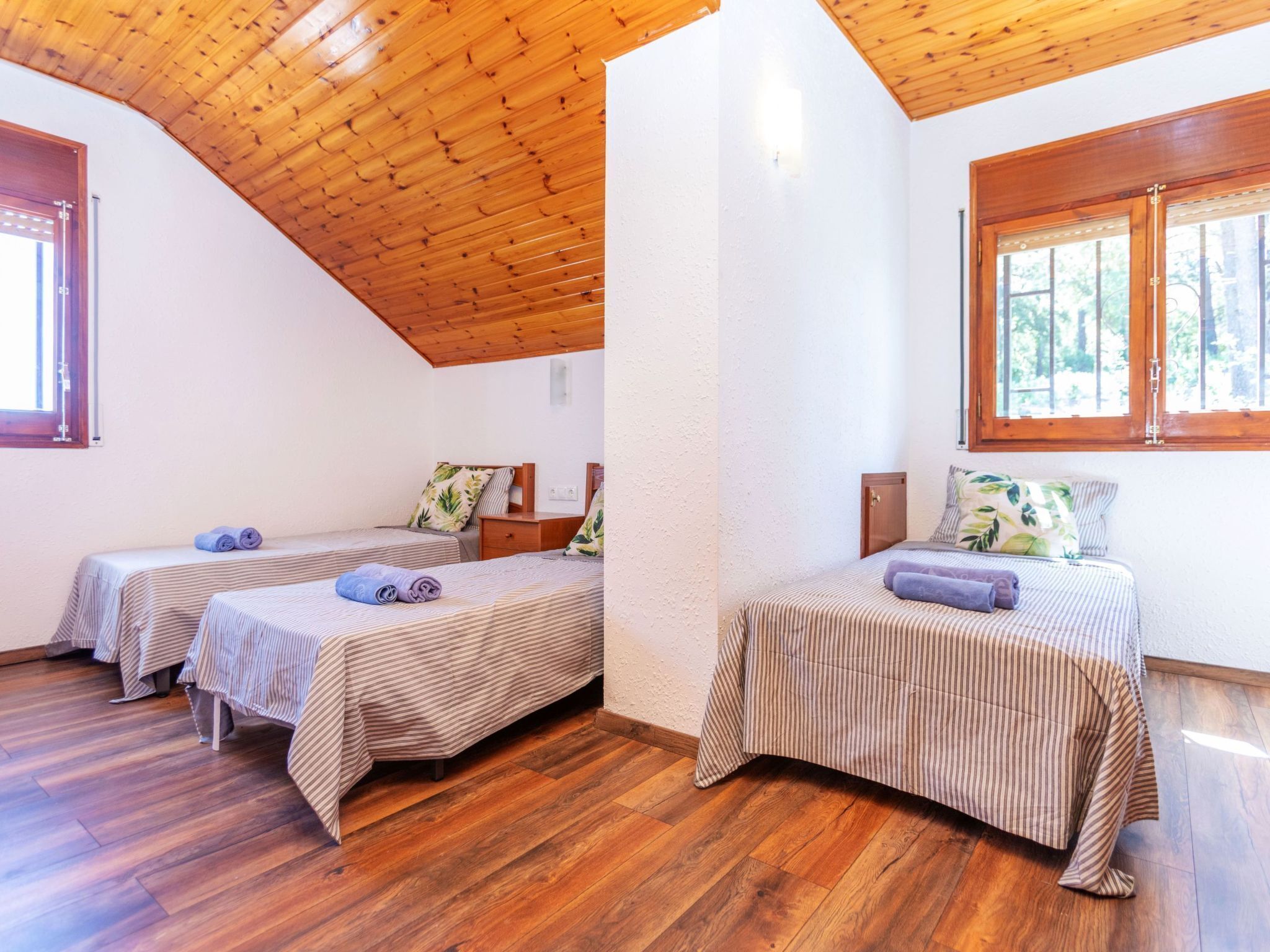 Una habitación con dos camas, suelo de madera y techo inclinado.