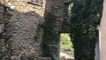 Un edificio de piedra con una ventana y un arco cubierto de hiedra.