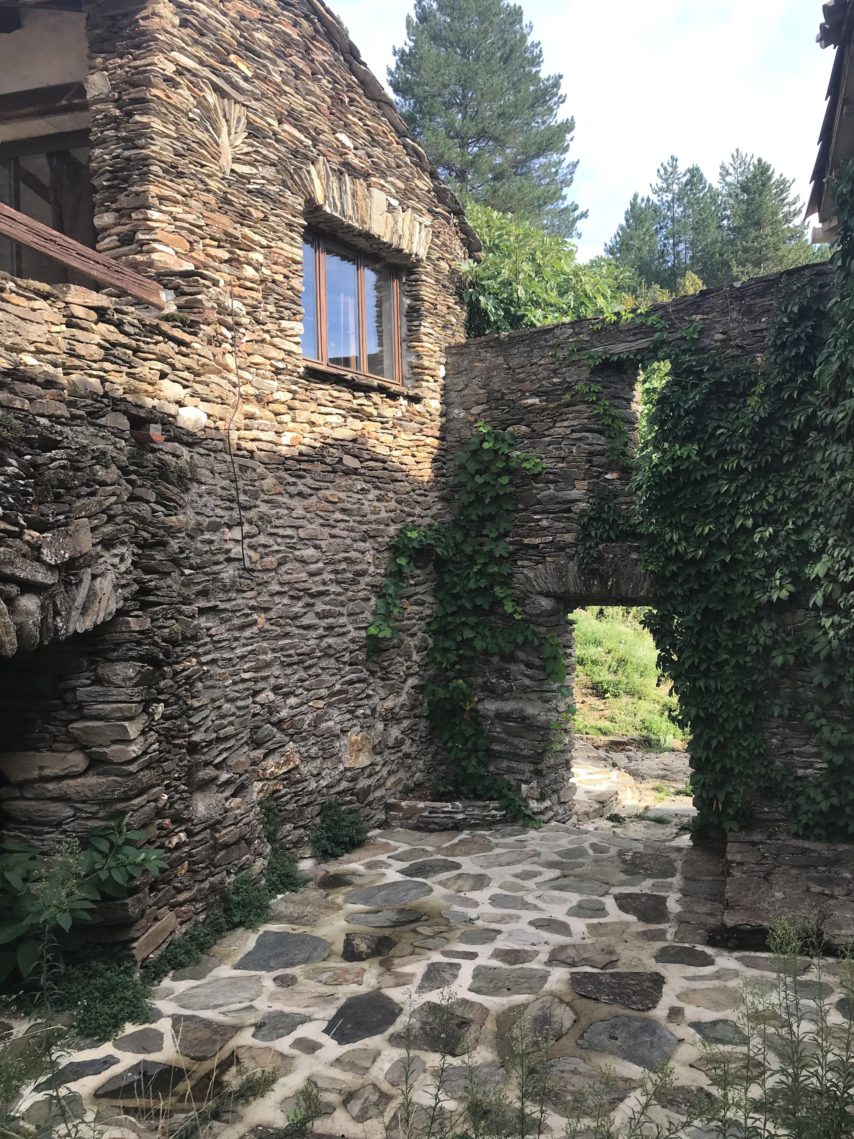 A stone building with a window and a stone pathway leading through an archway.