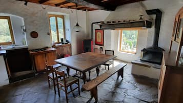 Una cocina rústica con una mesa de madera, suelo de piedra y un horno de leña.