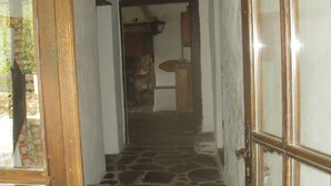 A stone-floored hallway with a wooden door and a window on the left.