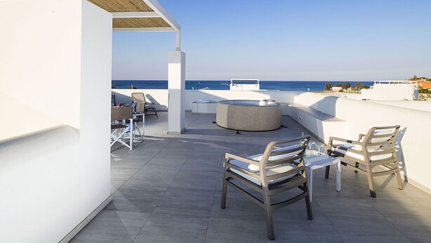 Une terrasse sur le toit offrant une vue sur la mer, avec des sièges extérieurs et un foyer.
