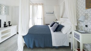 Une chambre à coucher avec un lit, des rideaux blancs, une table de chevet et une commode.