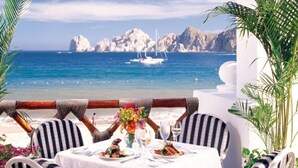 Zona de dinar a peu de mar amb una taula preparada per a dues persones, amb vista a l'oceà i els penya-segats.
