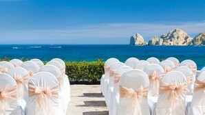 Preparació d'una cerimònia de casament amb cadires blanques i vista despejada a l'oceà i els penya-segats al fons.