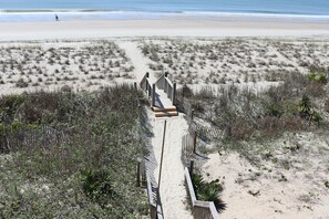 A sandy beach with a wooden boardwalk leading to the water.