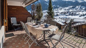Eine Terrasse mit Esstisch, Stühlen und Blick auf schneebedeckte Berge.