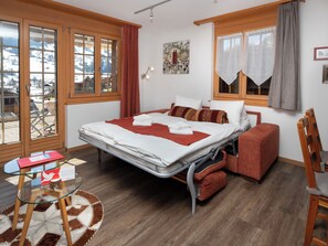 Une chambre à coucher avec un lit, une petite table, une chaise, un canapé et une vue sur l’extérieur.
