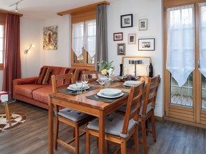 Un coin repas avec une table en bois dressée pour quatre personnes, un canapé et un mur orné de tableaux.