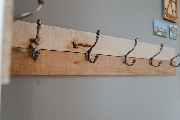 A wooden coat rack with five metal hooks against a wall. - Debonaire Suite: Modern - Calm - Downtown (Stratford)