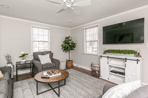 A living room with a grey sofa, a coffee table, a TV, and a plant. - * Stunning New Bungalow Perfect for Everyone * (Lutherville-Timonium)