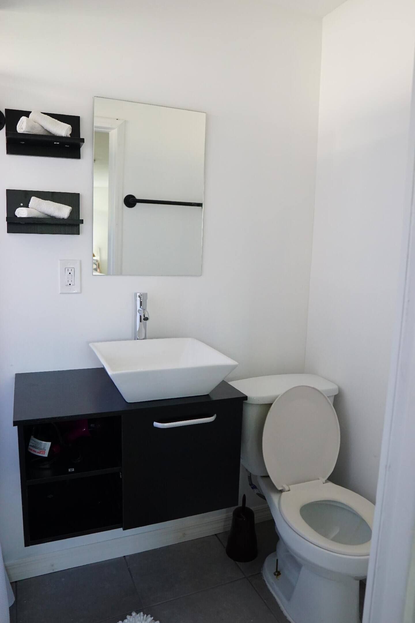 Un bagno moderno con un lavandino bianco, un mobile bagno nero e un water.