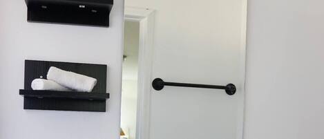 A bathroom with a white sink, black shelves with towels, a towel rack, and a mirror.