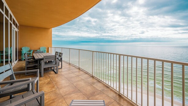 Un balcón con vista al mar, que incluye una mesa y sillas, y una barandilla.