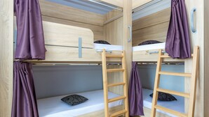 Une chambre avec un lit superposé en bois, des rideaux violets et une échelle.