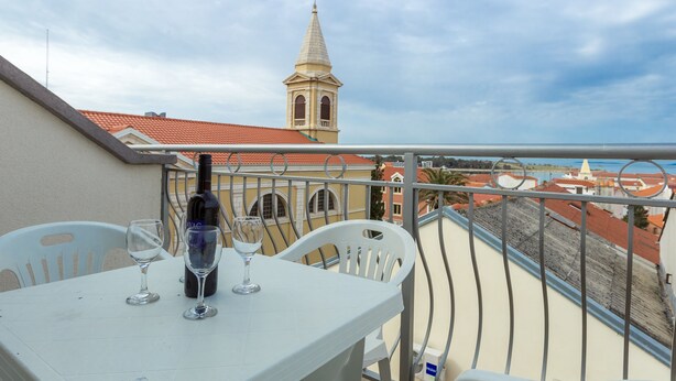 Un balcon avec une table, deux chaises et une bouteille de vin.
