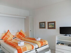 Una camera d'albergo con un letto, una televisione e due quadri appesi al muro.