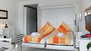 Una habitación de hotel con cama, escritorio, silla, televisor y armario.