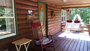 A wooden cabin with a porch, a rocking chair, a small table, and a door with a 'Help' sign.