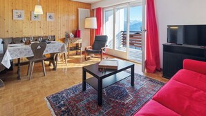 A living room with a dining area, a TV, and a view of mountains.