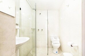 A bathroom with a glass shower enclosure, a toilet, and a sink. - Hotel Arena Plaza (Bogotá)
