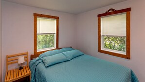 A bedroom with a bed, two windows, a nightstand, and a lamp. - Quaint & cozy home in DT Hood River, AMAZING Views off the privacy deck (Hood River)