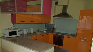 Una cocina con armarios color naranja, un microondas blanco, un fregadero y una estufa.