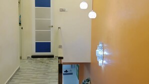 A hallway with a tiled floor, a blue door, and a wall-mounted light fixture. - The house is very strategic area. Nice and beautiful (Petaling Jaya)