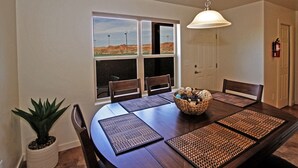 Un comedor con una mesa grande, sillas y vistas de un paisaje desértico a través de las ventanas.