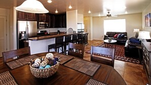 Una cocina moderna con armarios de madera oscura, electrodomésticos de acero inoxidable y un comedor con mesa y sillas de madera.