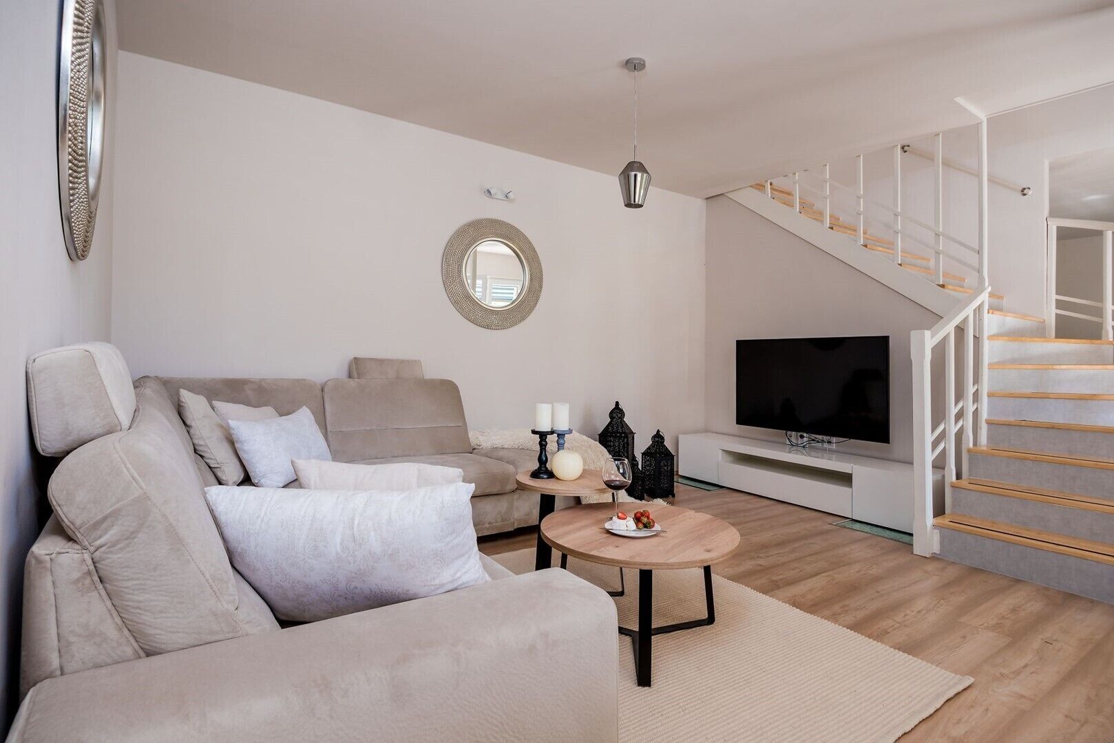 Un salon moderne avec un canapé, une table basse, un téléviseur et un escalier.