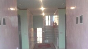 Un pasillo con alfombra roja y diseño estampado que lleva a una escalera.