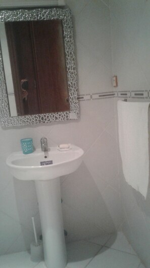 A bathroom with a white sink, a mirror with a decorative frame, and a towel hanging on the wall.