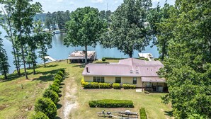 Une propriété au bord du lac comprenant une grande maison, un quai et une remorque pour bateau.