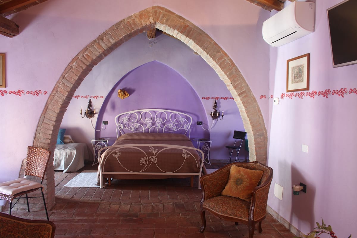 Ein Schlafzimmer mit einem Bett, einem Sessel und einer gewölbten Ziegeldecke.