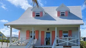 Ein zweistöckiges Haus mit einer Veranda, einer Treppe und einem Schild, das "Coconut Row" zeigt.