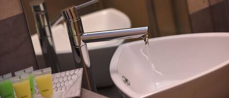 A bathroom sink with running water, a mirror, and toiletries.