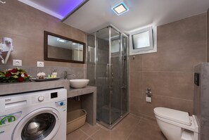 Enjoy a bright and inviting bathroom with a glass-enclosed shower, standalone sink, and washing machine.