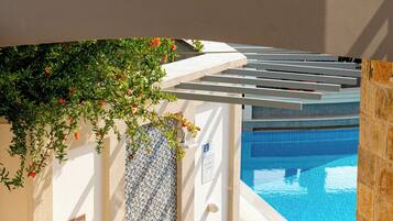 A pool area with a pergola, a wall-mounted emblem, and a tiled wall.