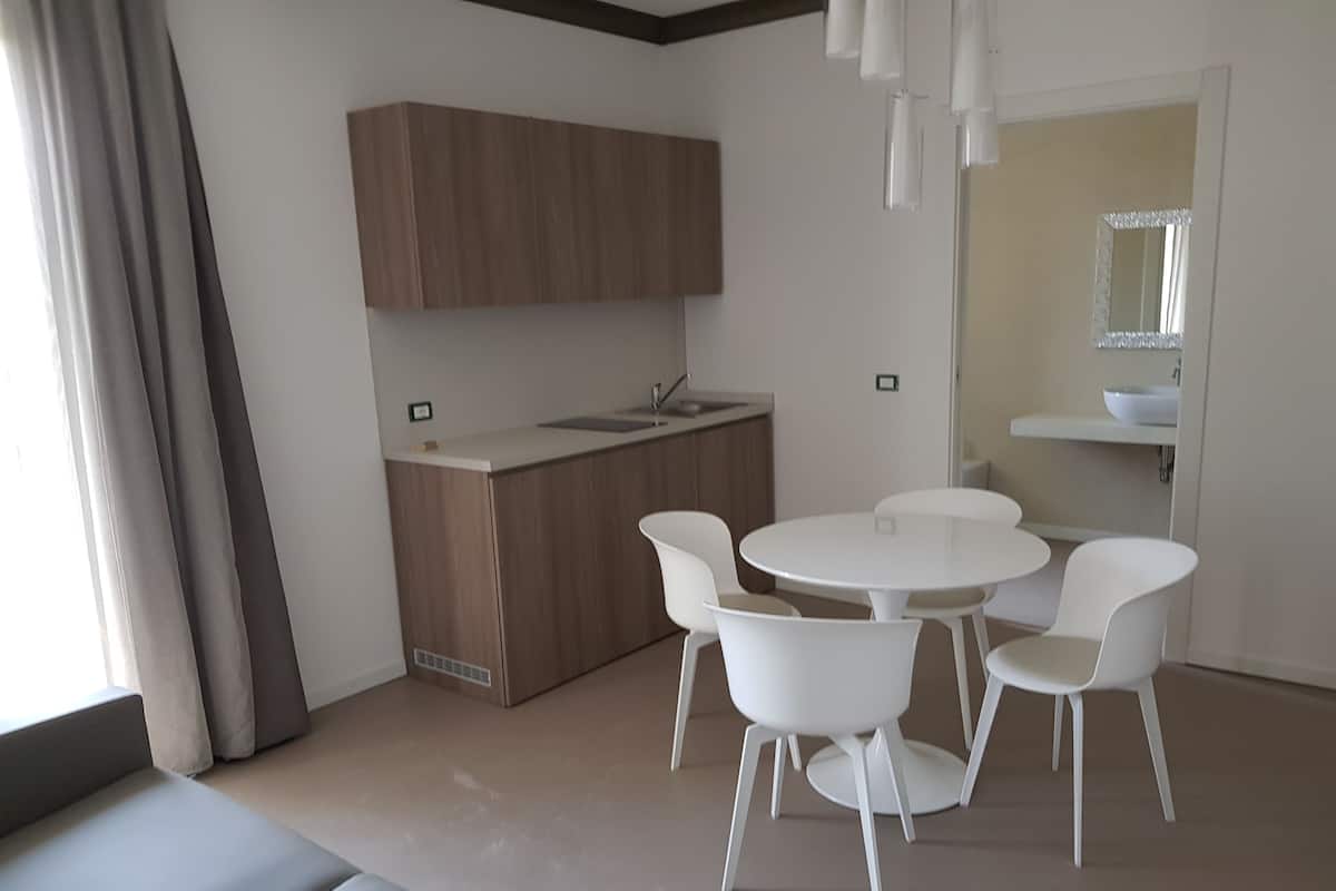Una cocina moderna con horno empotrado, un lavamanos y una zona de comedor con una mesa redonda y cuatro sillas.