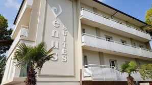 Un edificio con un cartel que dice "Venues Suites" y balcones con barandillas.