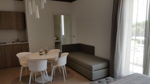 Una sala de estar moderna con un sofá gris, una mesa de comedor con sillas y una zona de cocina con armarios de madera.