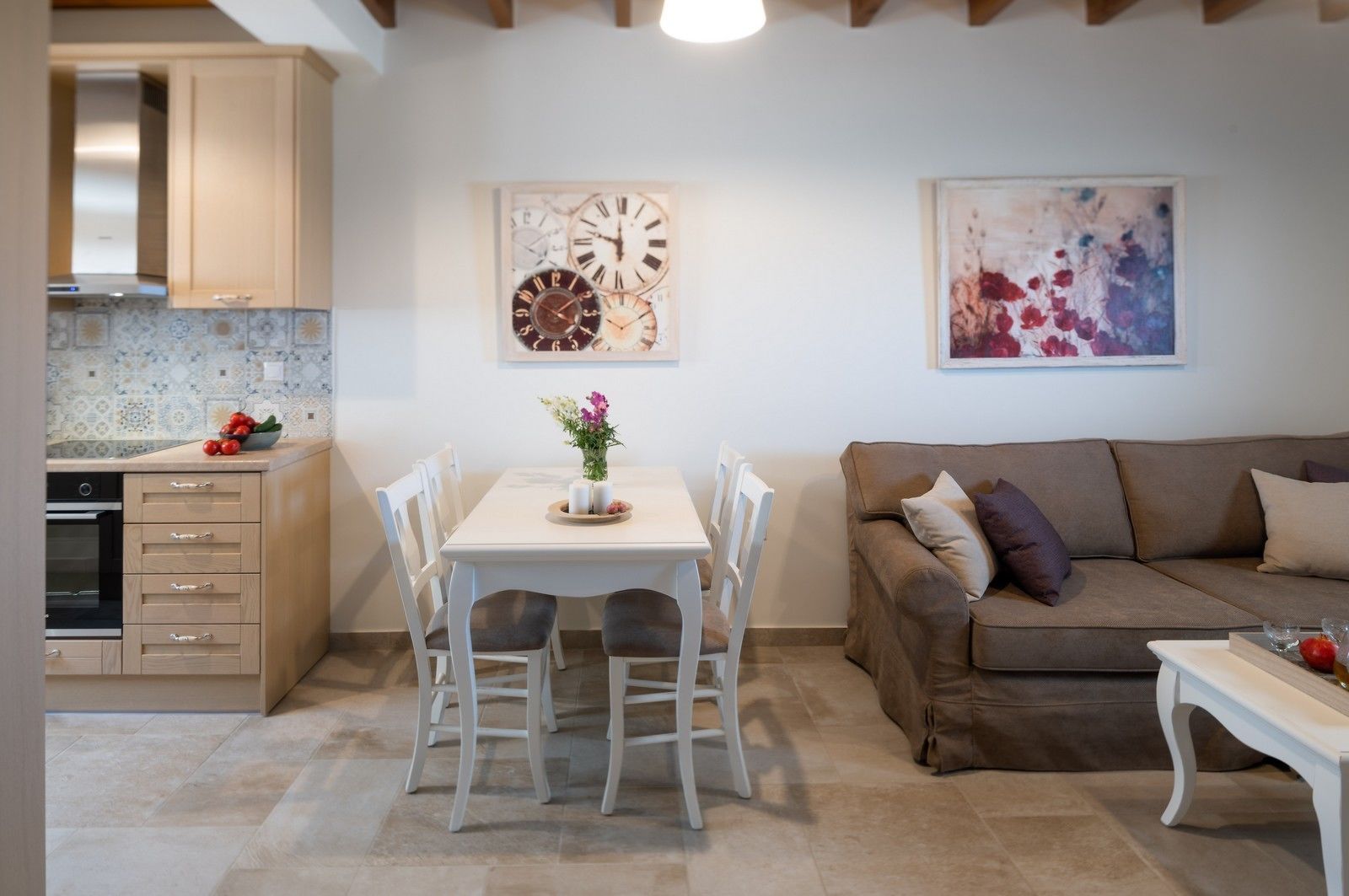 A modern kitchen with a dining table and chairs, a sofa, and a painting on the wall.