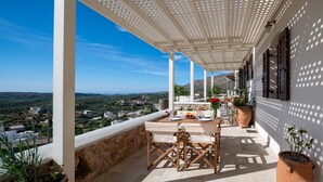 A terrace with a table and chairs, a view of the landscape, and potted plants. - Cretan Minoan Apartments (Sitia)