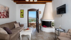 A living room with a fireplace, a sofa, a coffee table, and a TV. - Cretan Minoan Apartments (Sitia)