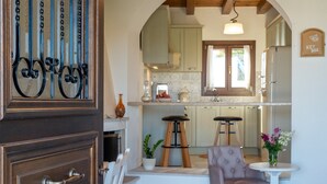 A cozy kitchen with wooden stools, a small table, and a decorative vase. - Cretan Minoan Apartments (Sitia)