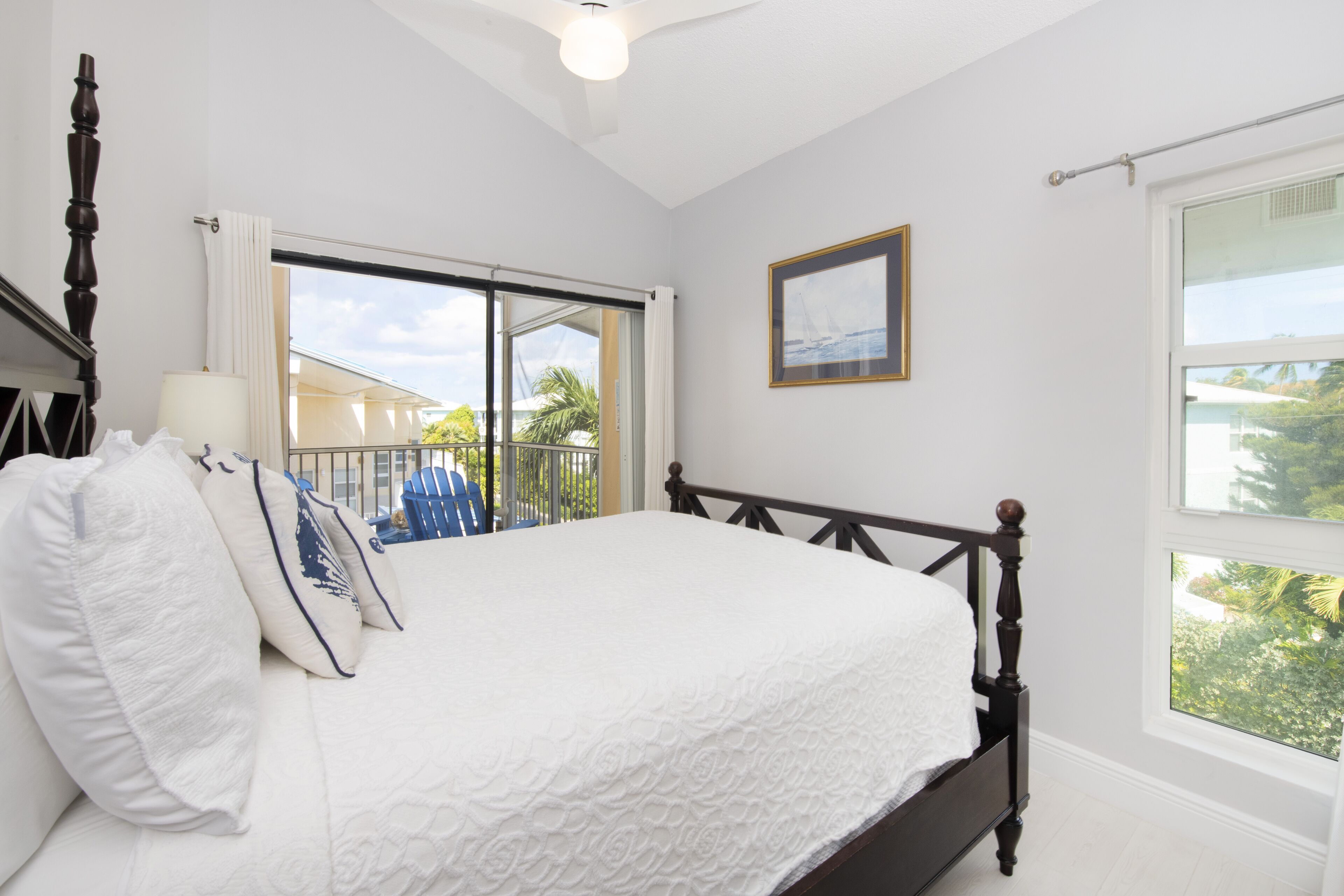 A bedroom with a large bed, a window with a view of the outdoors, and a ceiling fan.