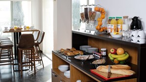 A breakfast buffet with various food items, beverages, and a coffee station.
